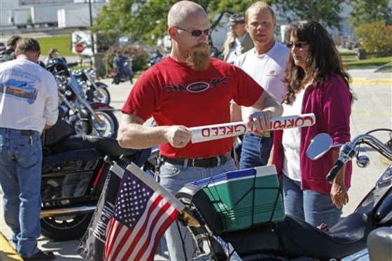 A Harley-Davidson worker rolls up a poster he had on his motorcycle after voting at the Waukesha Exposition Center in Waukesha, Wi., Monday, Sept. 13, 2010. Union workers ratified a seven-year labor contract. (AP Photo/Jeffrey Phelps)